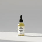 Botanical hair growth serum bottle with dropper on a light gray background