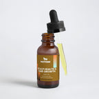 Bottle of Nestdeer scalp health and hair growth hair oil with a dropper on a light gray background.