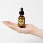 Hand holding a bottle of 'Nest Deer' scalp health and hair growth oil against a light background.