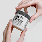 Jar of Nestorian Recovery Cream held by hands against a neutral background