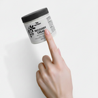 Hand pointing to a jar of 'Recovery Cream' on a light gray background
