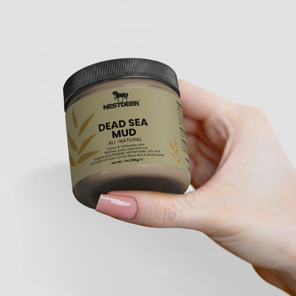 Hand holding a jar of Nestdeer Dead Sea Mud against a light background