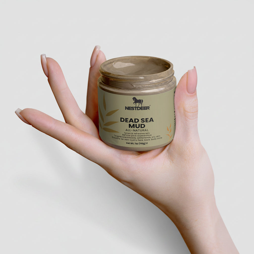 Hand holding a jar of Nesther Dead Sea Mud on a light background