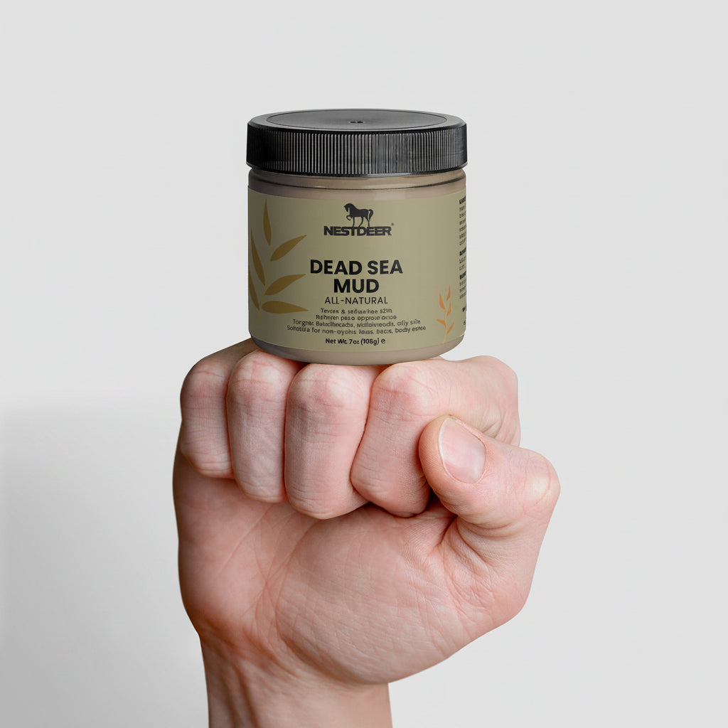 Hand holding a jar of Nestlève Dead Sea Mud on a gray background