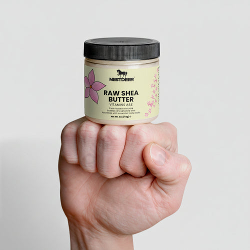 Hand holding a jar of Northbeeh Raw Shea Butter against a light gray background