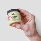 Hand holding a jar of Nestlé Raw Shea Butter against a light background