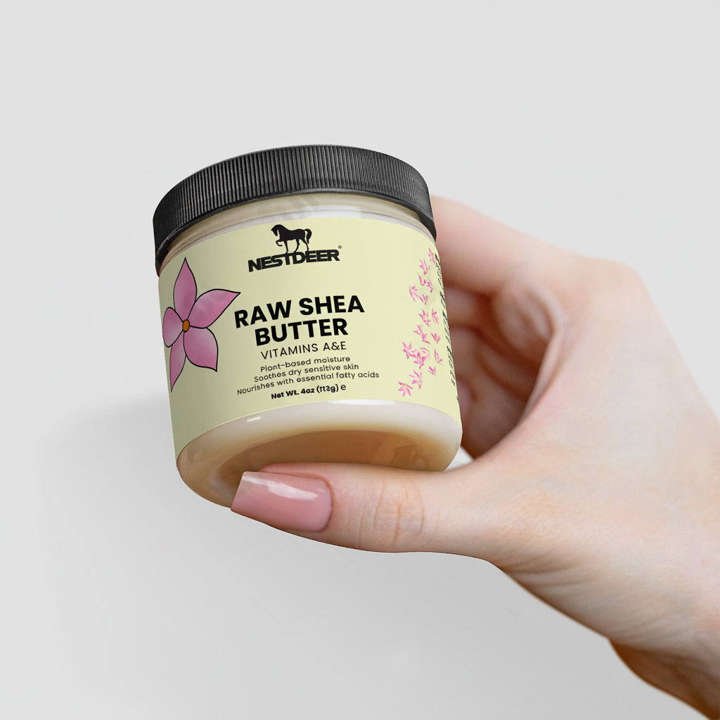 Hand holding a jar of Nestder Raw Shea Butter against a light background